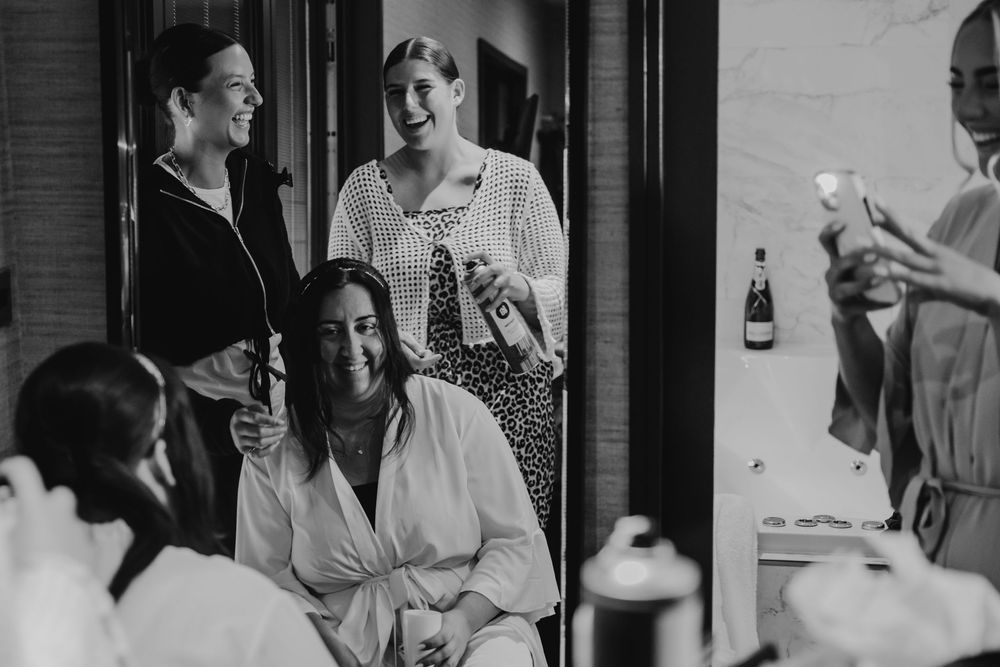Black and white candid moments captured during wedding day preparations in a room.
