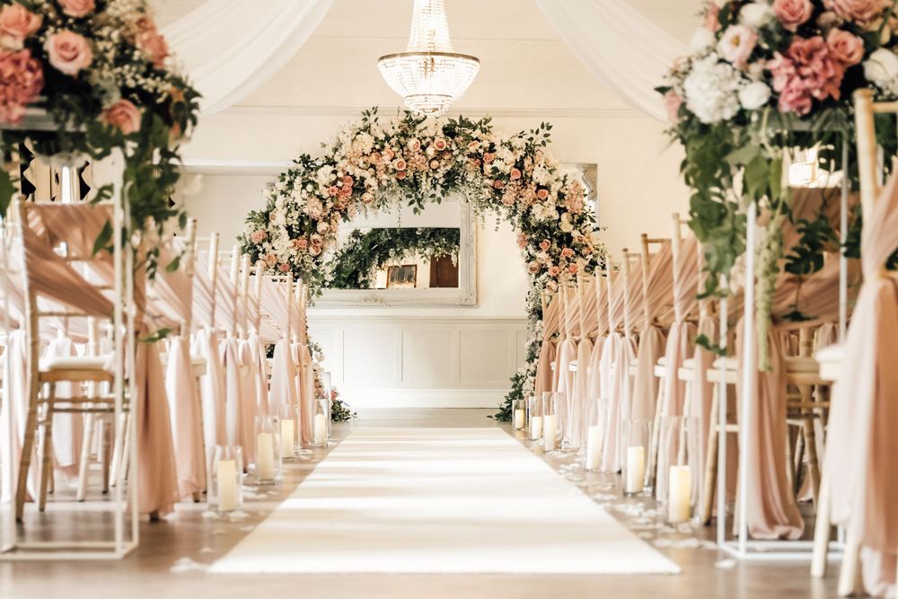 Elegant wedding aisle decorated with pink floral arrangements and white draping.