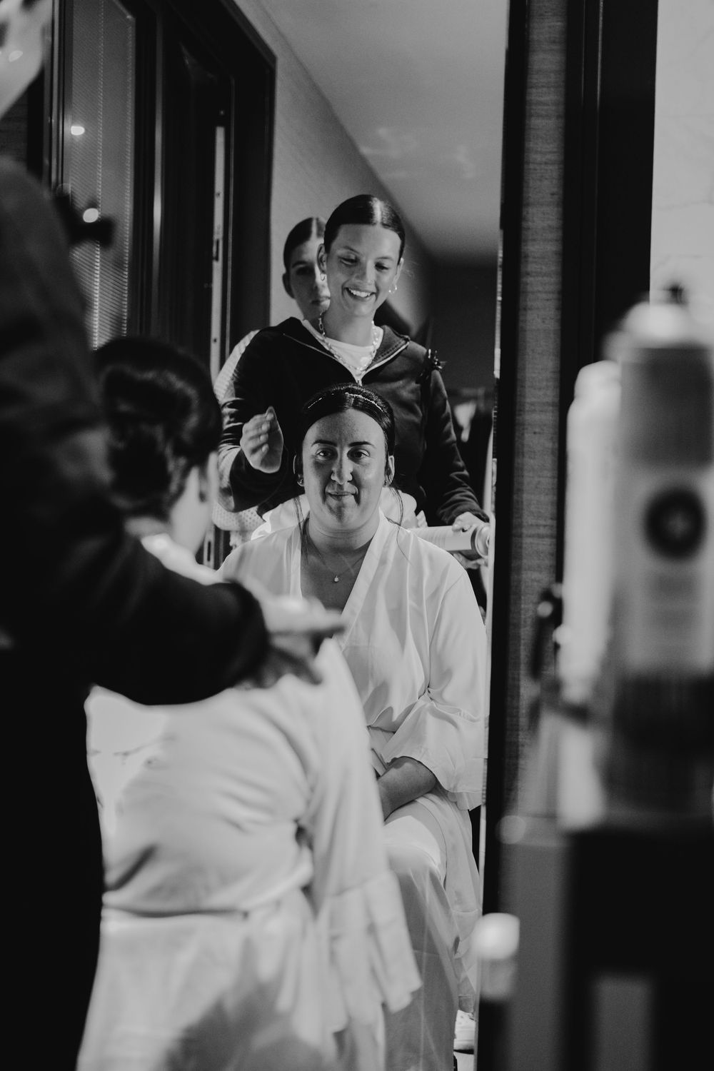 Black and white candid moments of wedding day preparations in a brightly lit room.
