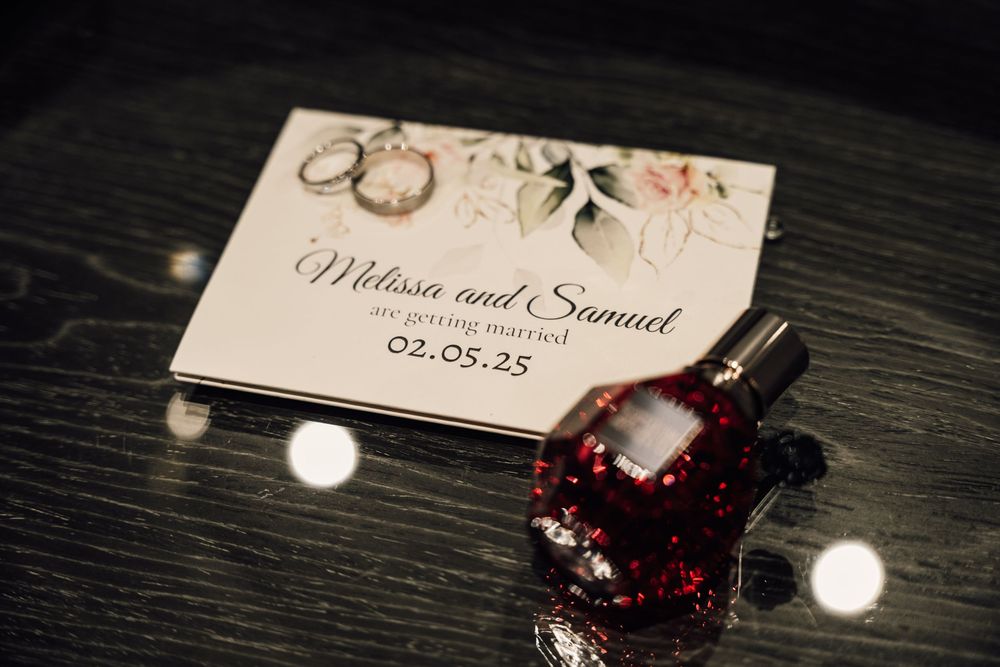 Wedding invitation details with deep red floral accents on dark wooden surface.