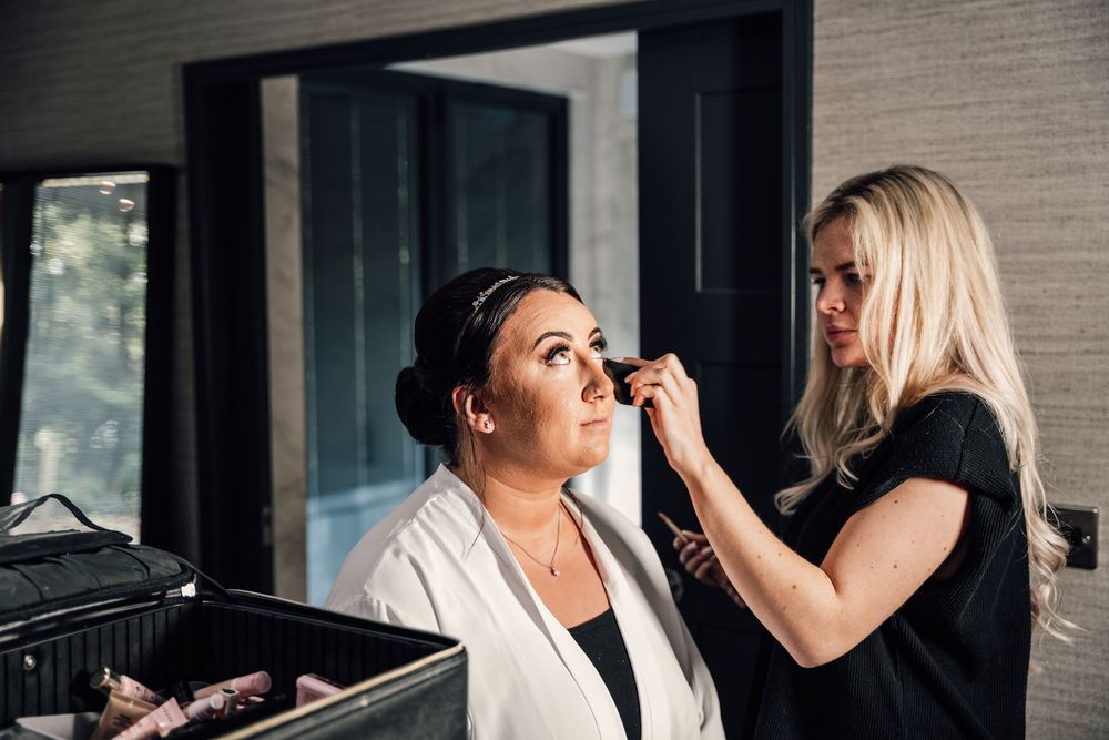 Wedding makeup preparations in progress in a naturally lit room with white robes.