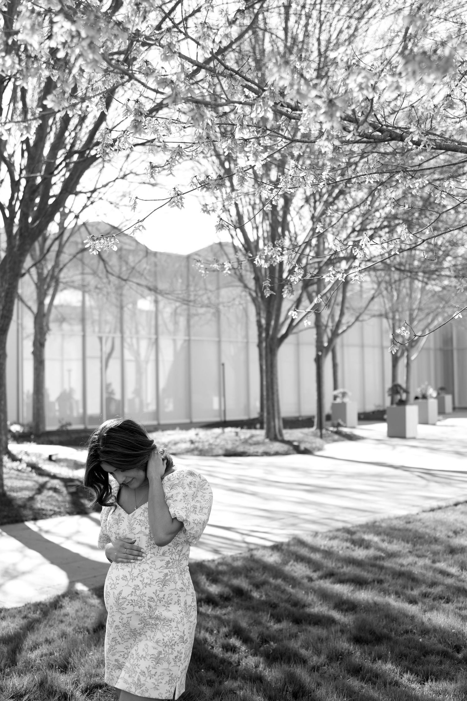 Black and white photo of person in lace dress among blooming trees.