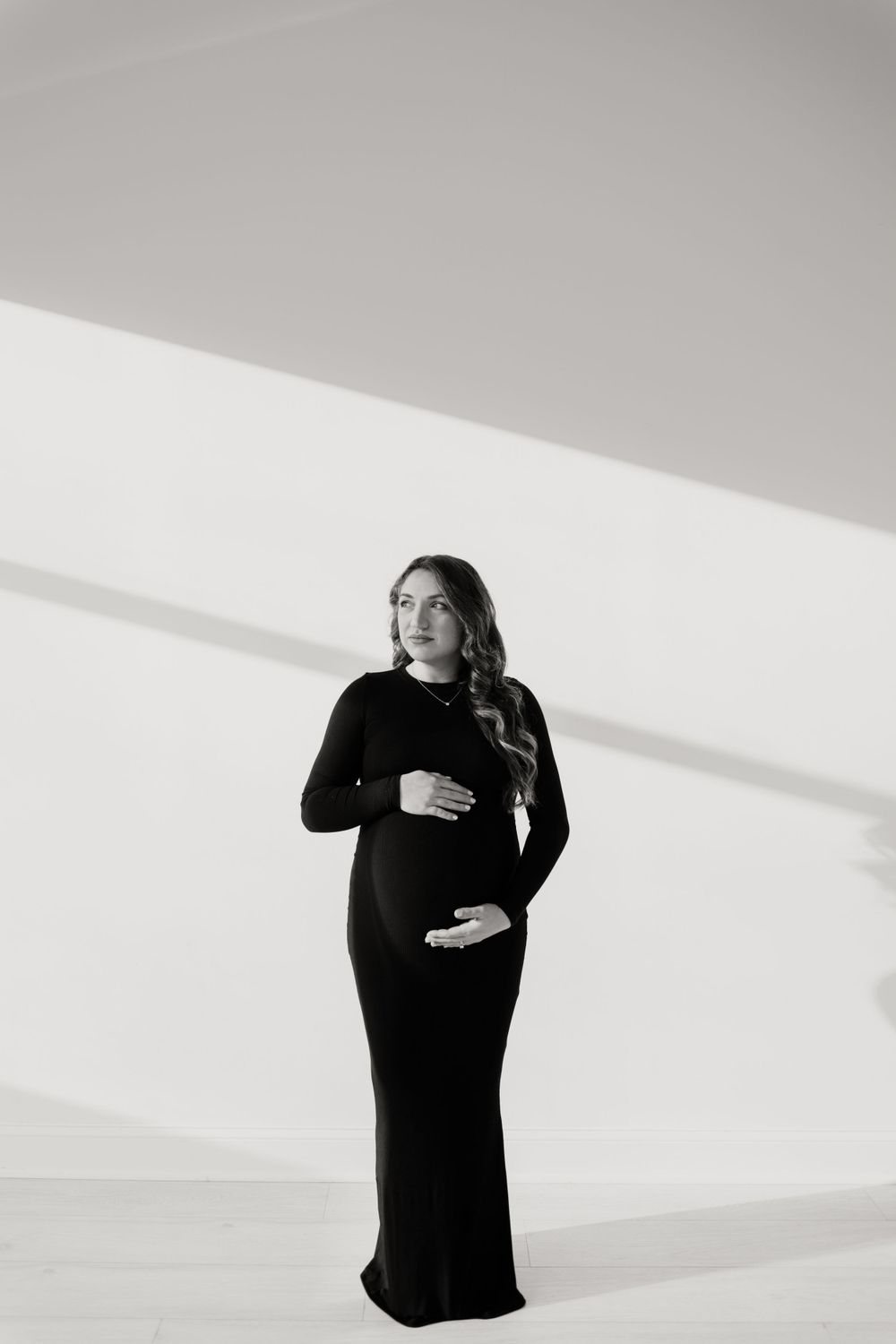 Dramatic black and white portrait of pregnant woman in long black dress.