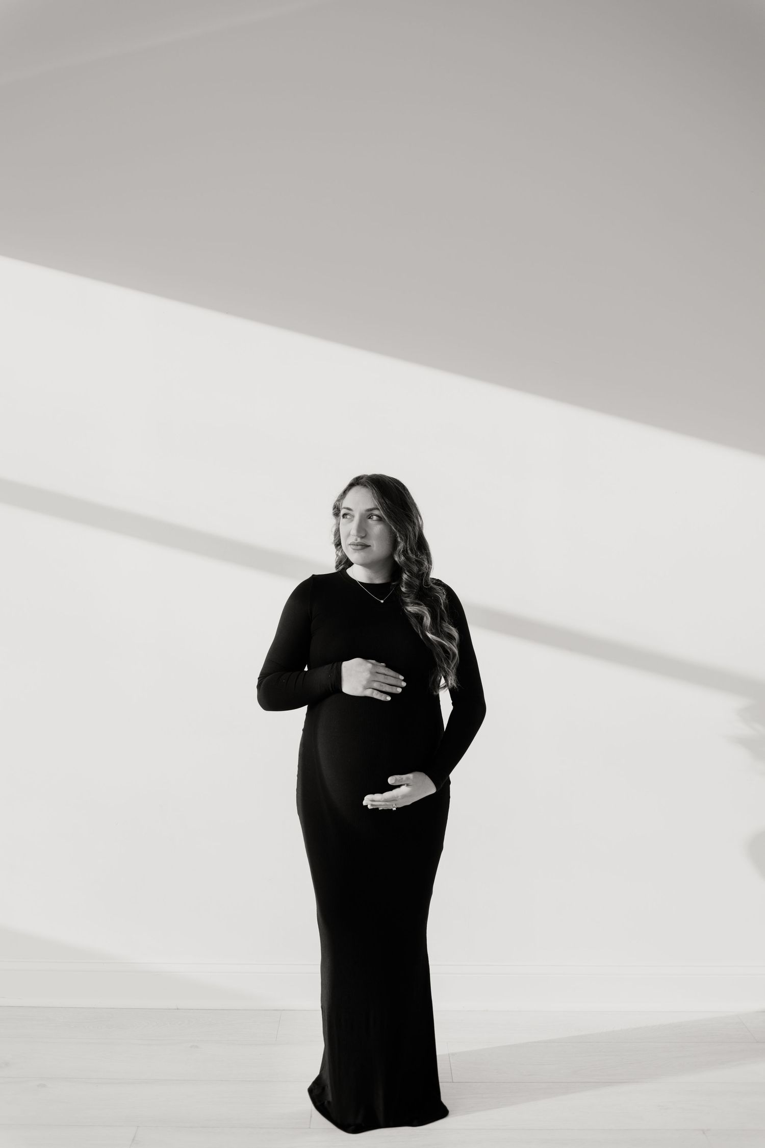 Dramatic black and white portrait of pregnant woman in long black dress.