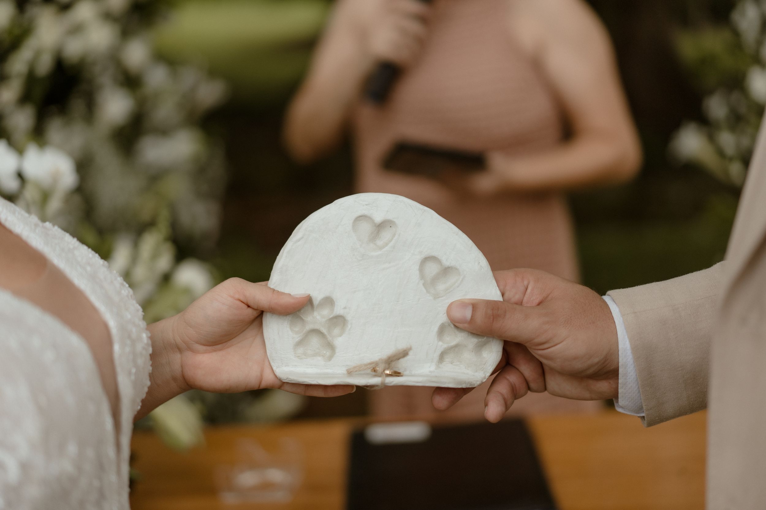 Couple sharing cake at their wedding ceremony in an outdoor garden setting.