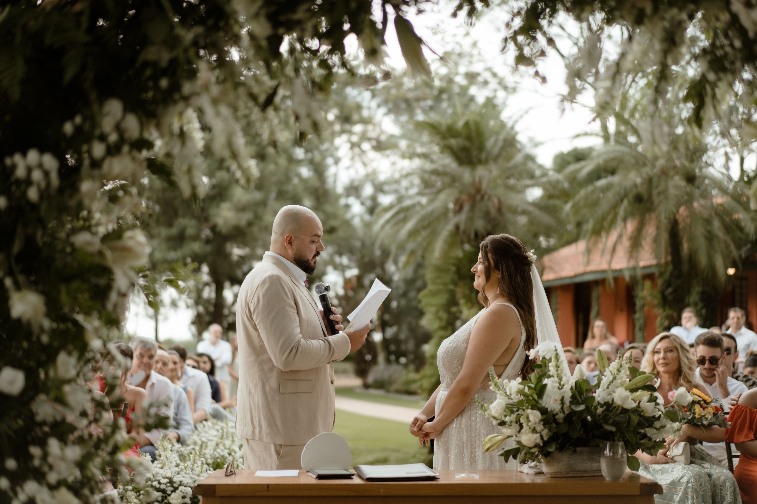 Outdoor wedding ceremony setup with rows of wooden chairs and floral arrangements.