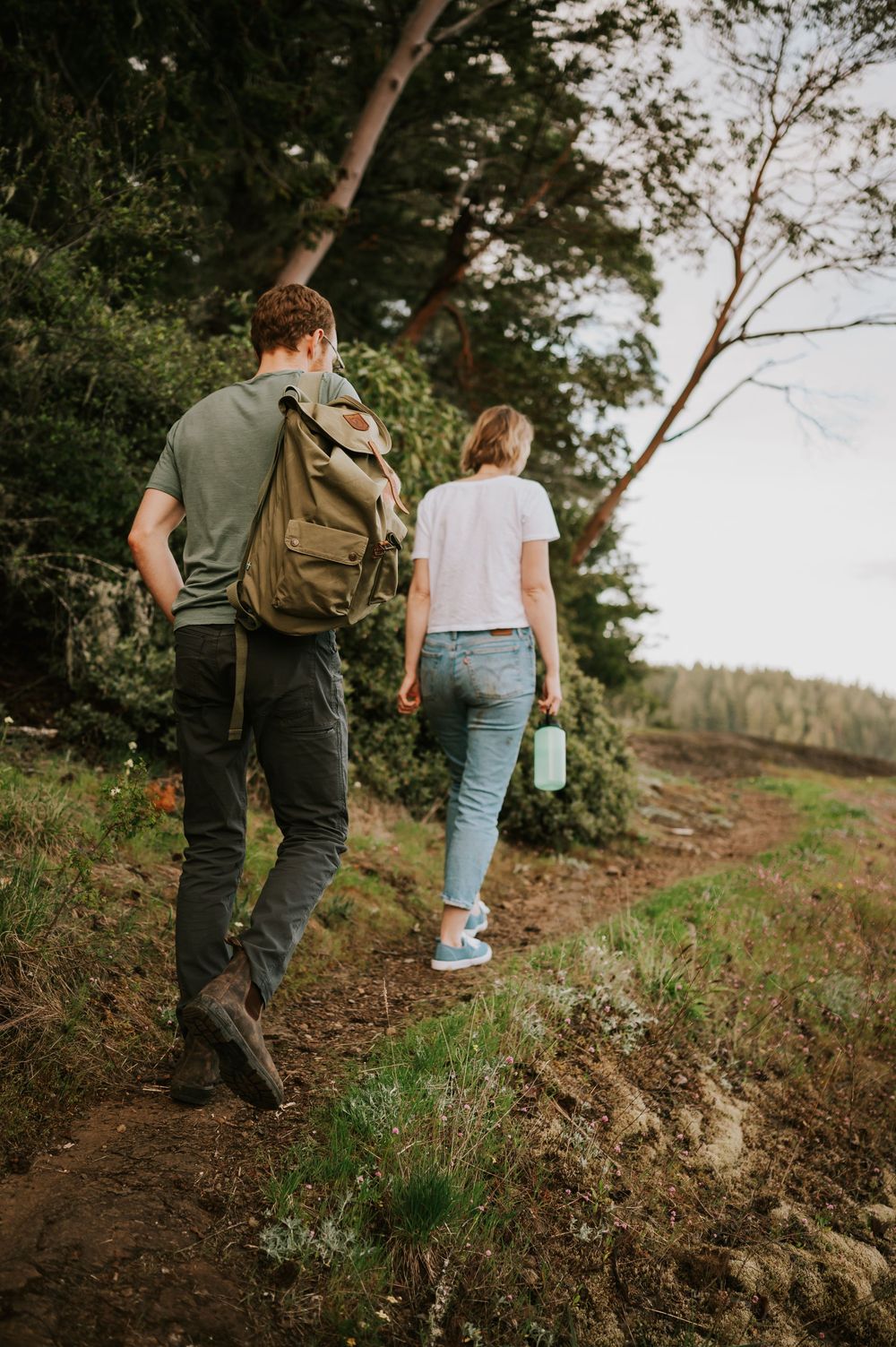 Couple walking together along forest trail near Comox Lake Bluffs, peaceful and natural engagement photo moment