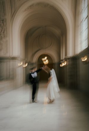 A dreamy, motion-blurred wedding scene in a grand hallway with arched ceilings and soft glowing lights.