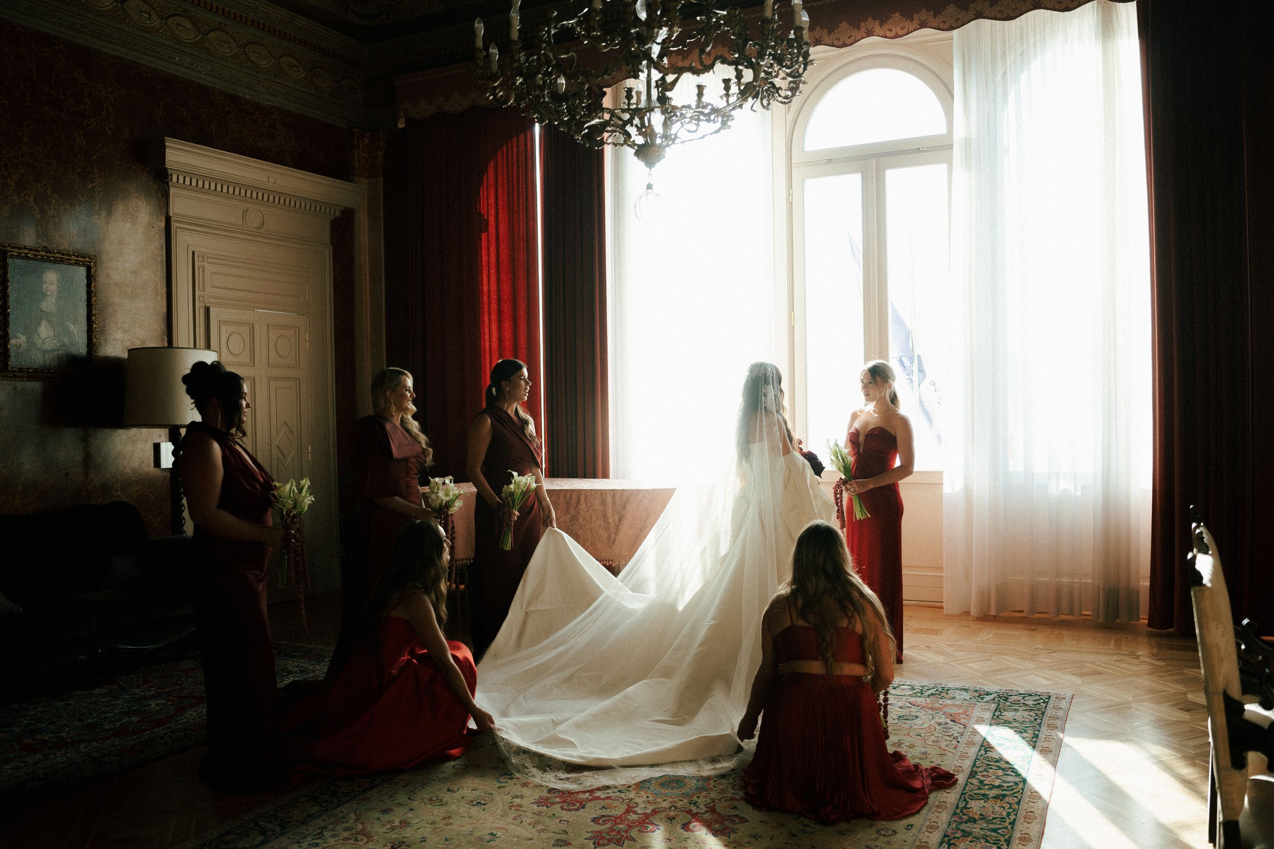 Silhouetted figures stand in front of bright sunlit windows in a rustic wooden room creating dramatic lighting effects.