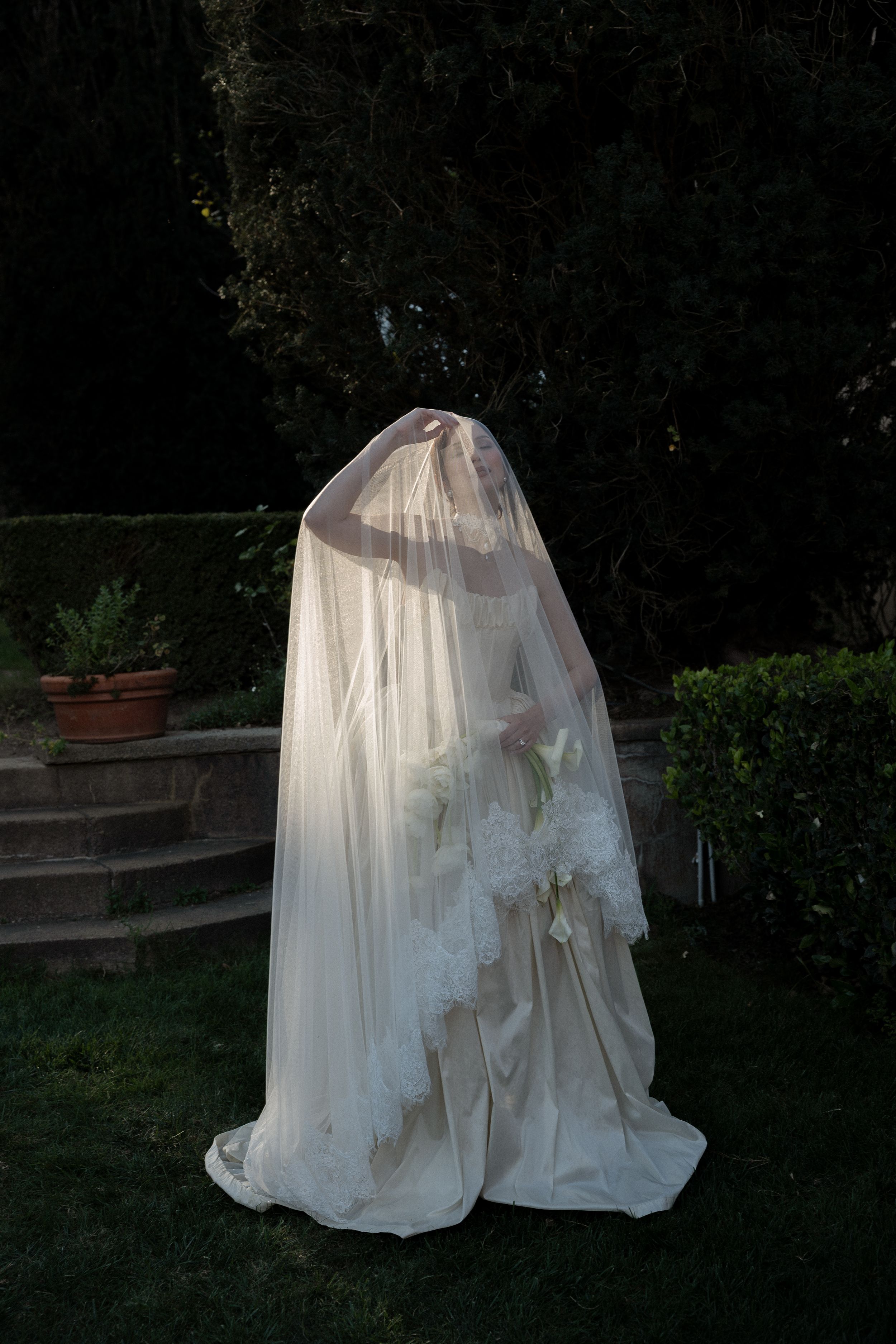 Two ghostly figures draped in white sheets stand in a dark garden setting creating a spooky Halloween atmosphere.