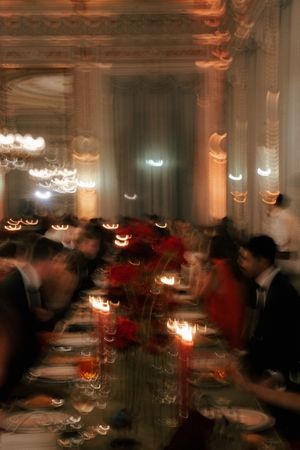 Blurred motion shot of an elegant dining room with candlelit tables and warm ambient lighting creating a romantic atmosphere.