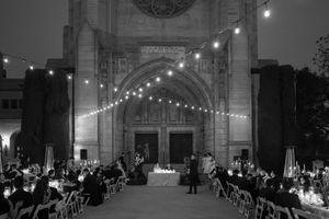 Black and white panoramic view of an elegant wedding reception venue with string lights and ornate architectural details.
