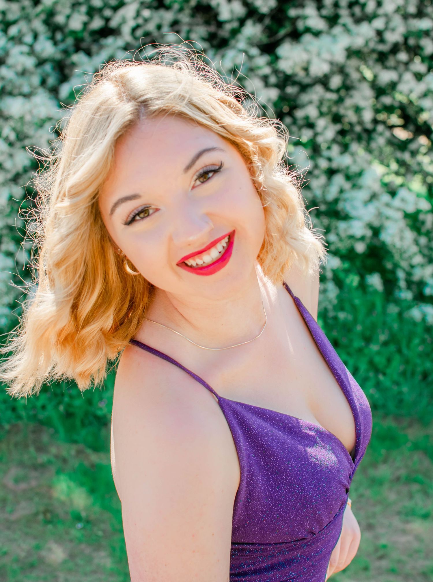 Portrait in purple dress against green foliage background.