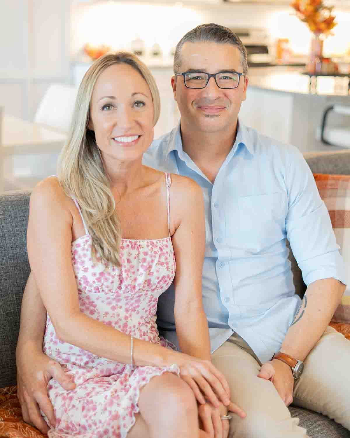A couple poses together on a couch in a bright, modern living room.