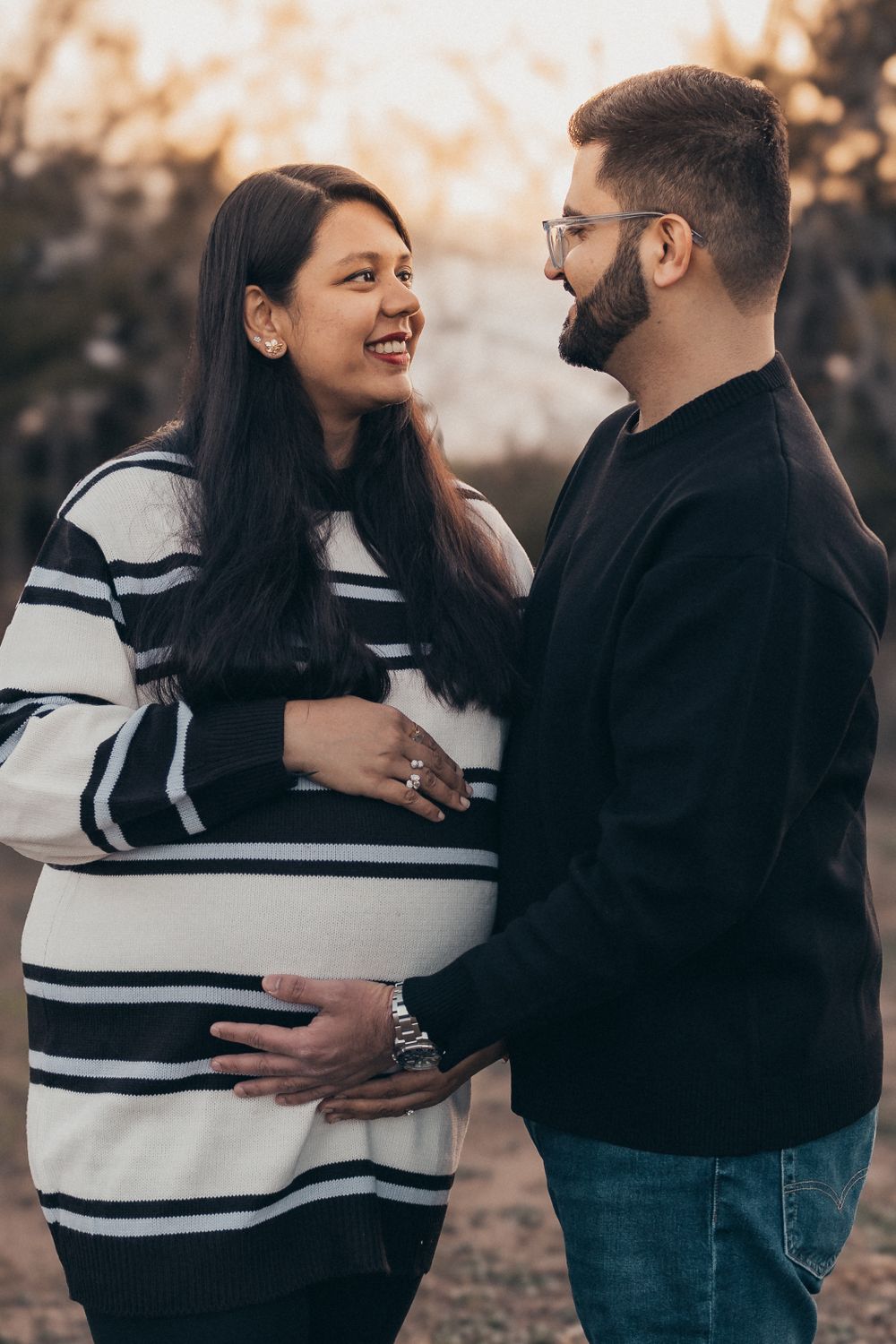An expectant couple shares an intimate moment outdoors during a pregnancy photoshoot.