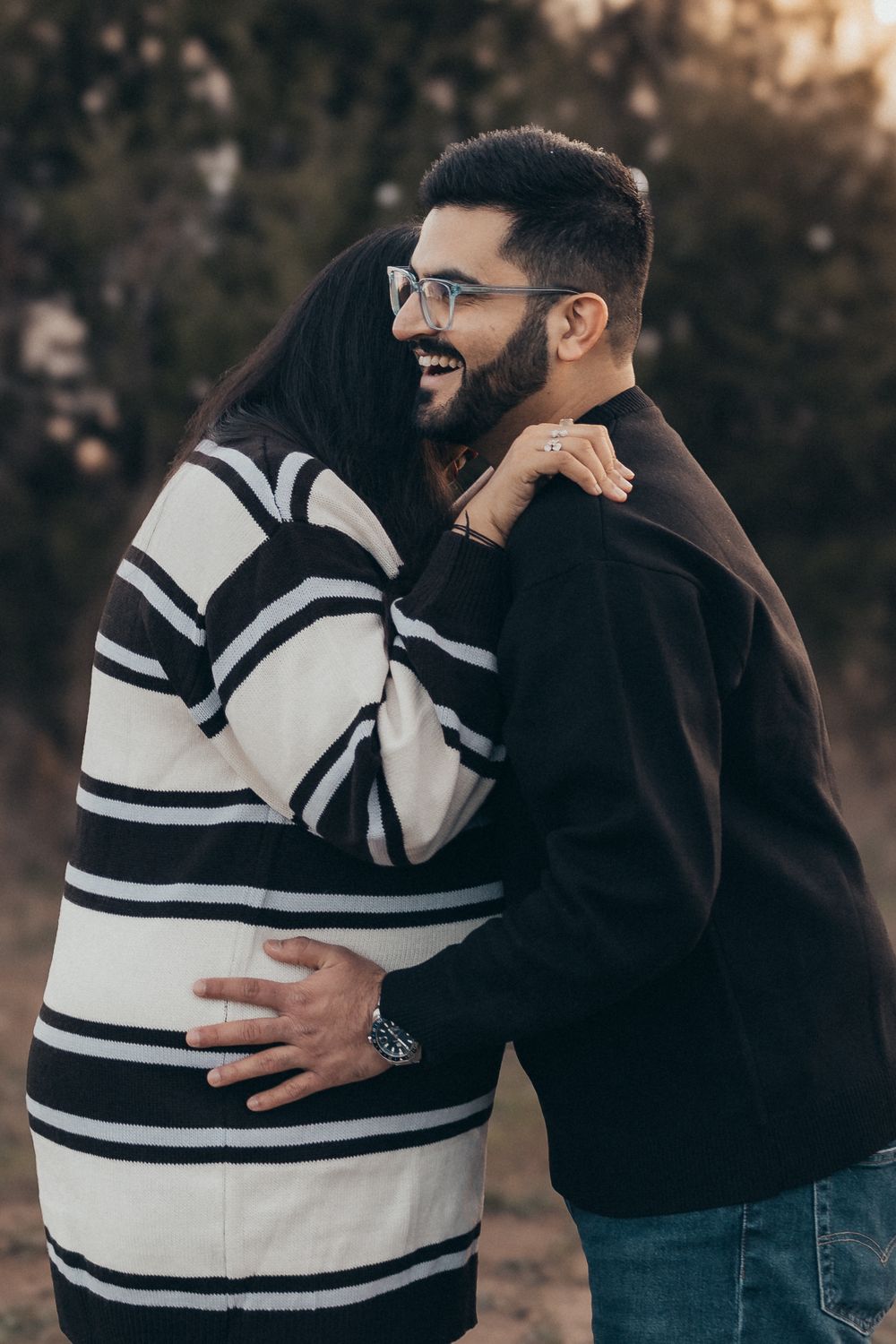 A couple shares a candid laughing moment during an outdoor photoshoot.