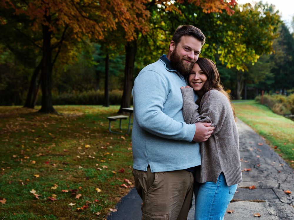 A couple shares tender moments together during an autumn photoshoot in a park with colorful fall foliage.