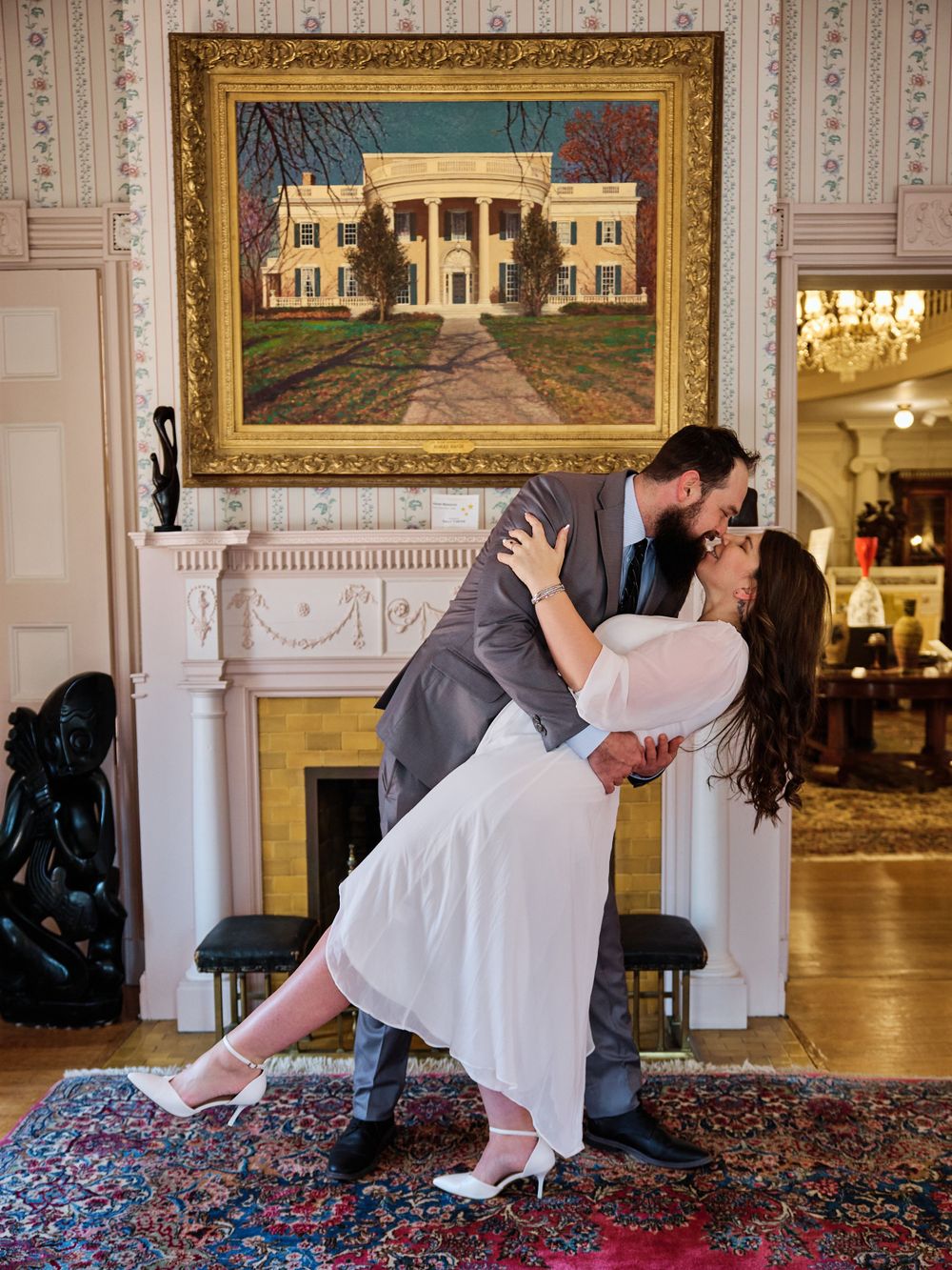 A romantic vintage ballroom scene with an ornate framed mansion painting and elegant oriental rug.