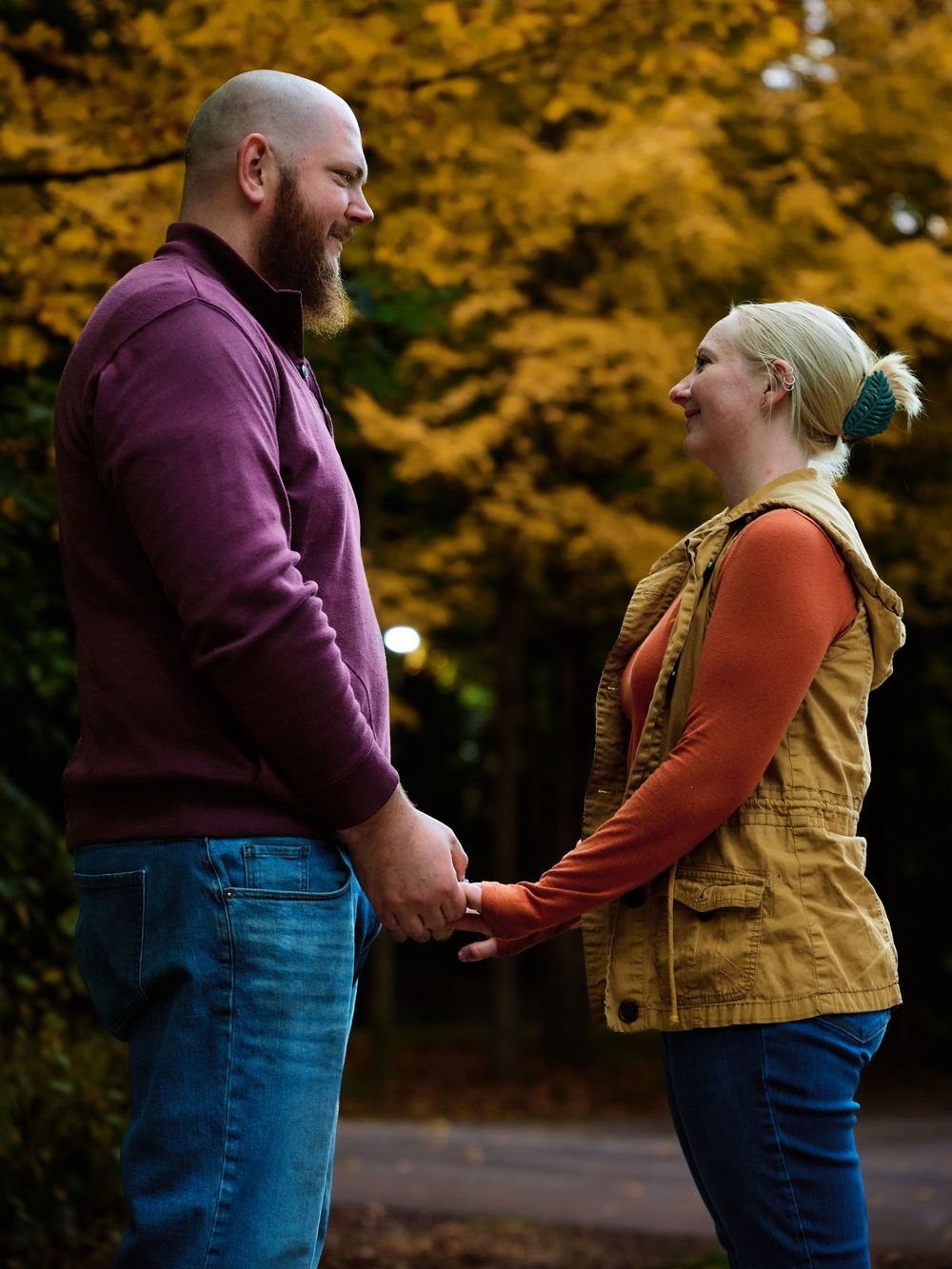 A couple shares a tender moment together against a backdrop of vibrant autumn foliage in a romantic outdoor setting.