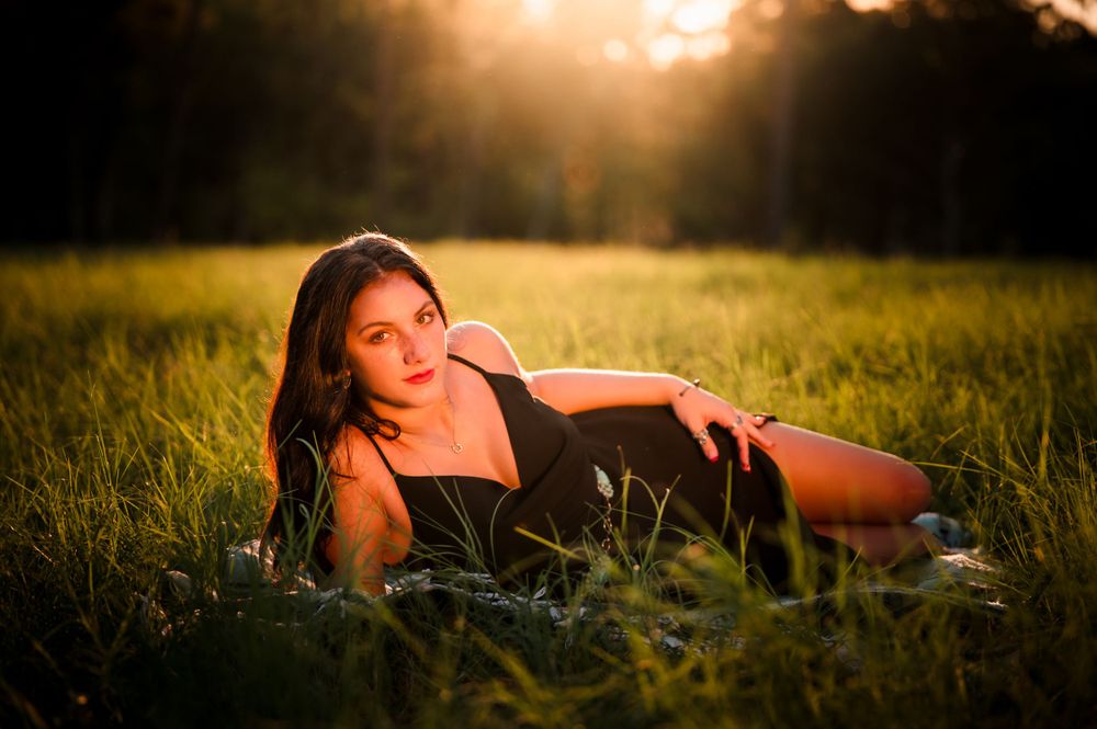 Person lounging in grassy field during golden hour sunset.