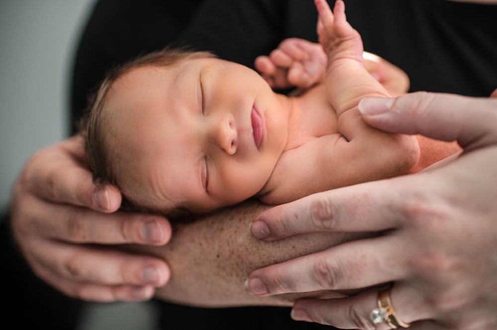 Peaceful sleeping newborn baby lies gently cradled in loving hands.