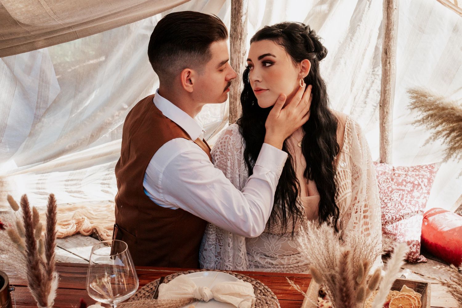 A cozy indoor engagement session featuring a couple sharing a rustic picnic setup with dried florals and warm earth-toned details in a boho-