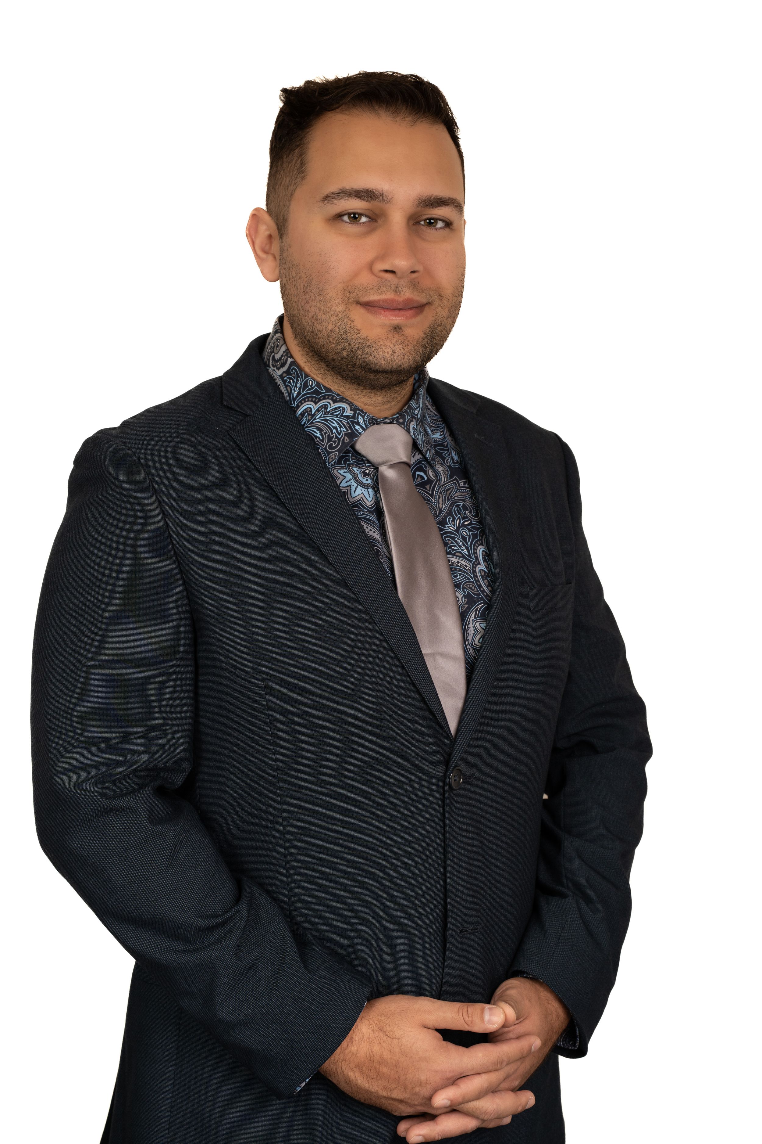 Professional headshot of someone wearing a dark suit and patterned tie against a plain background.