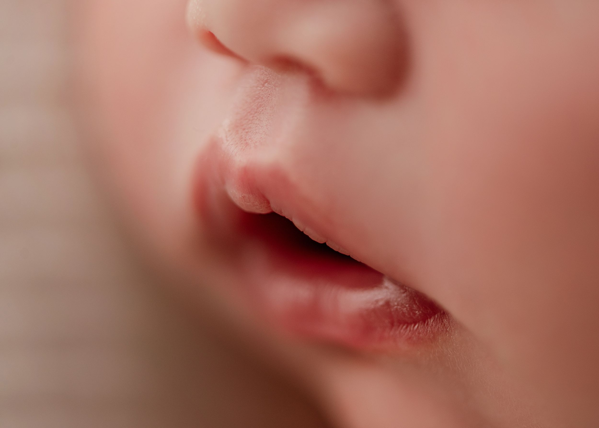 Extreme close-up macro photograph of pink baby lips and nose in soft focus.