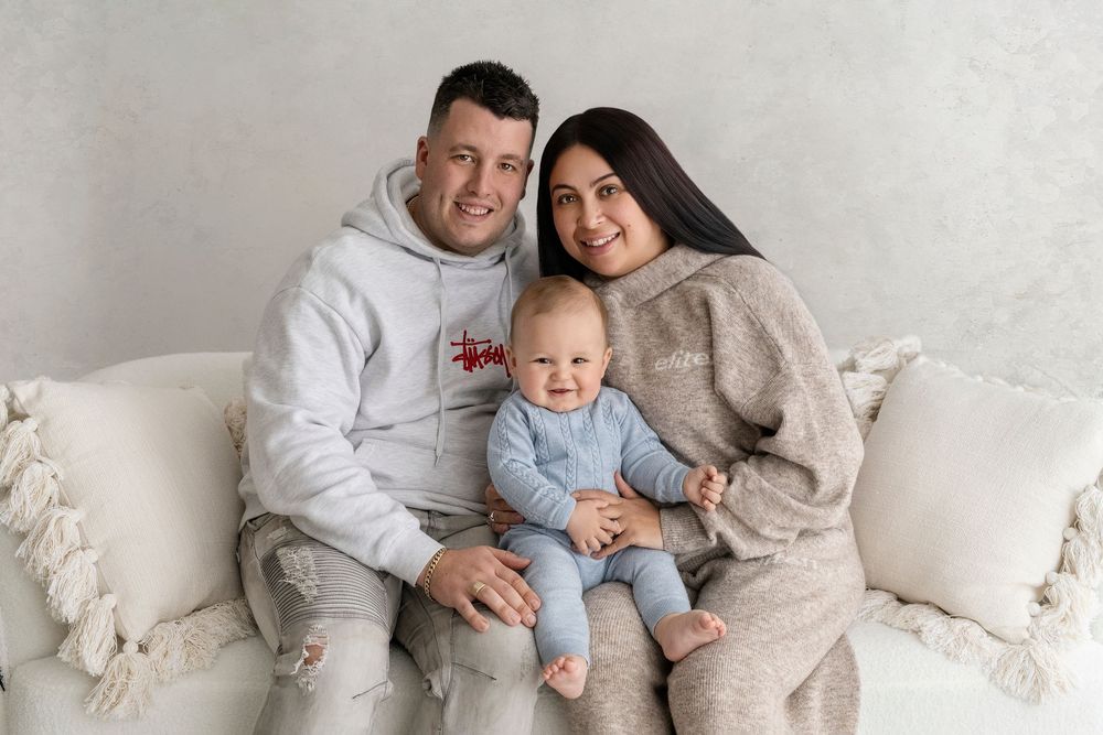 Family sitting together on white furniture during an indoor photoshoot.