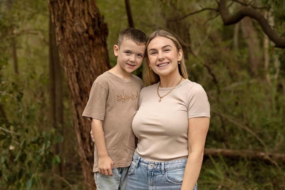 Natural family portraits captured in front of tall trees and greenery.
