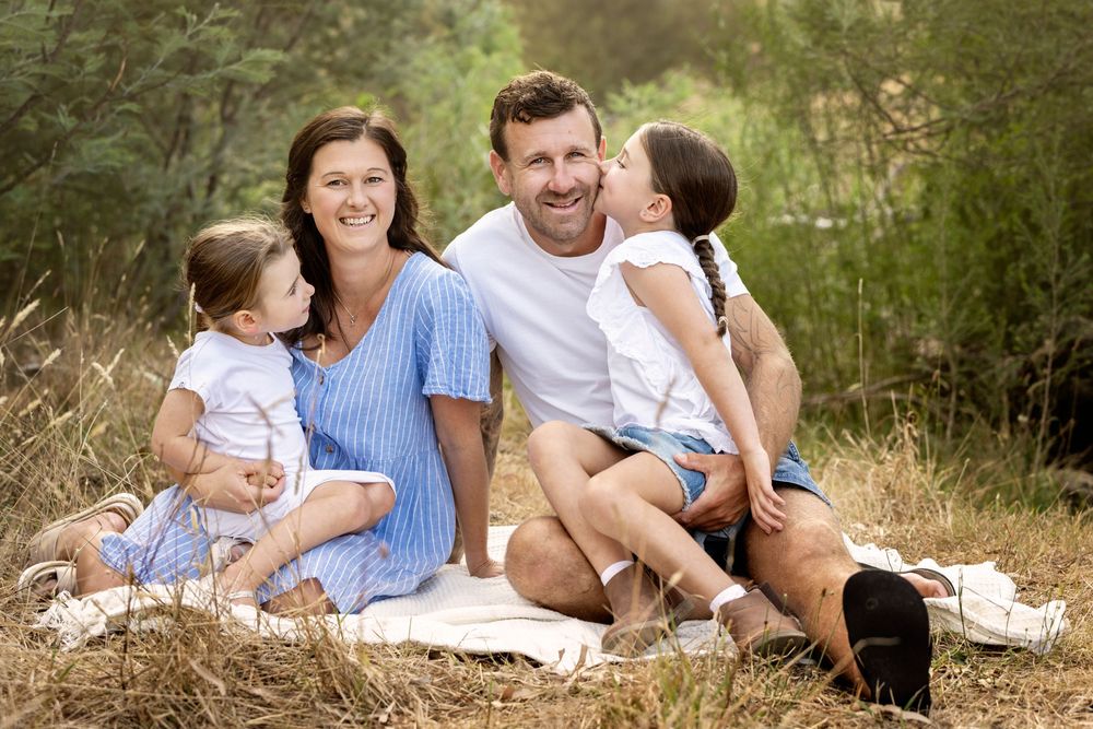 Family relaxing together outdoors on a blanket during a summer photoshoot.