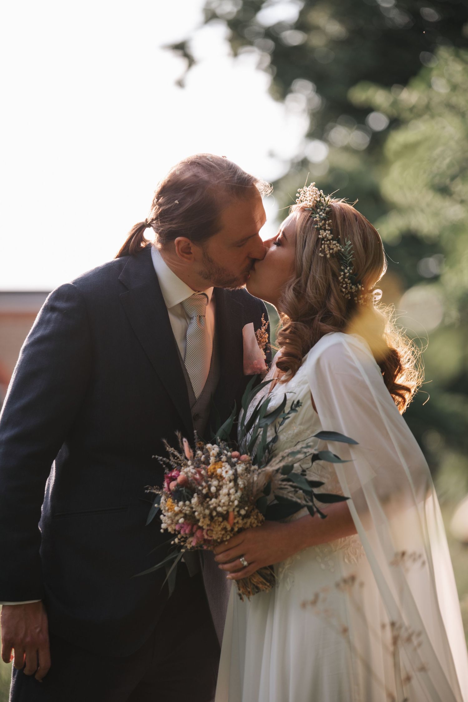 Outdoor wedding ceremony with couple sharing romantic moment while holding floral bouquet.