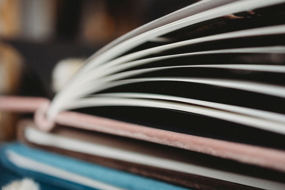 Macro close-up view of fanned book pages shows crisp white paper edges against a blurred background.