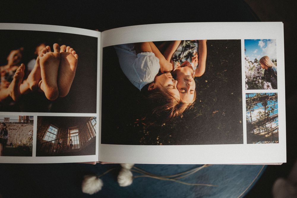 An open photo album showing artistic photography layouts with baby feet and other lifestyle images on its pages.