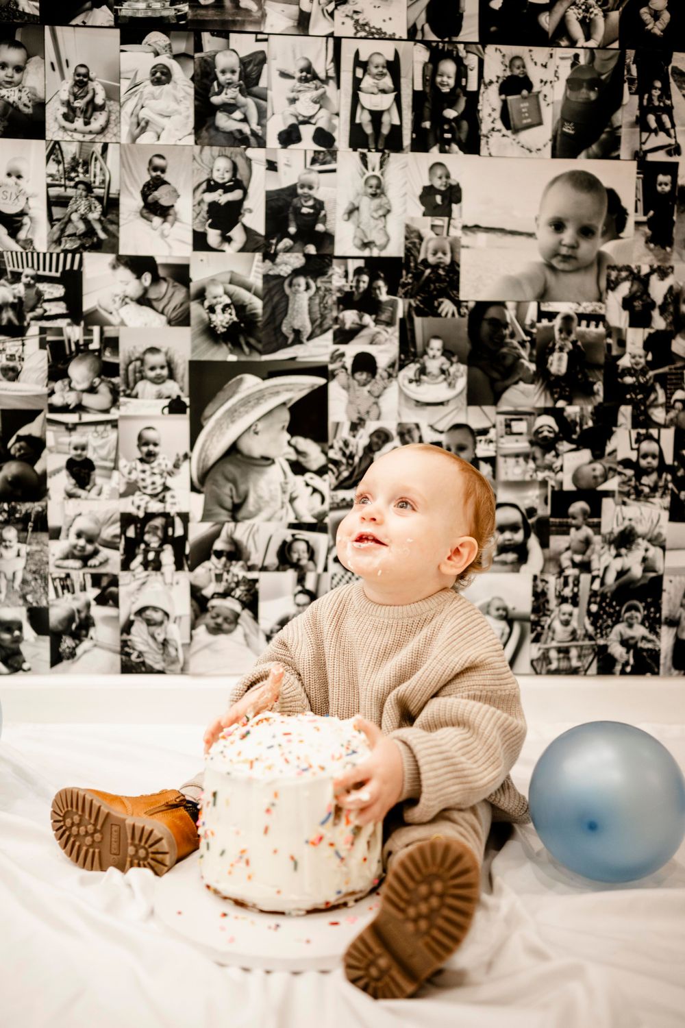 Baby in knit sweater sitting with birthday cake against photo collage background.
