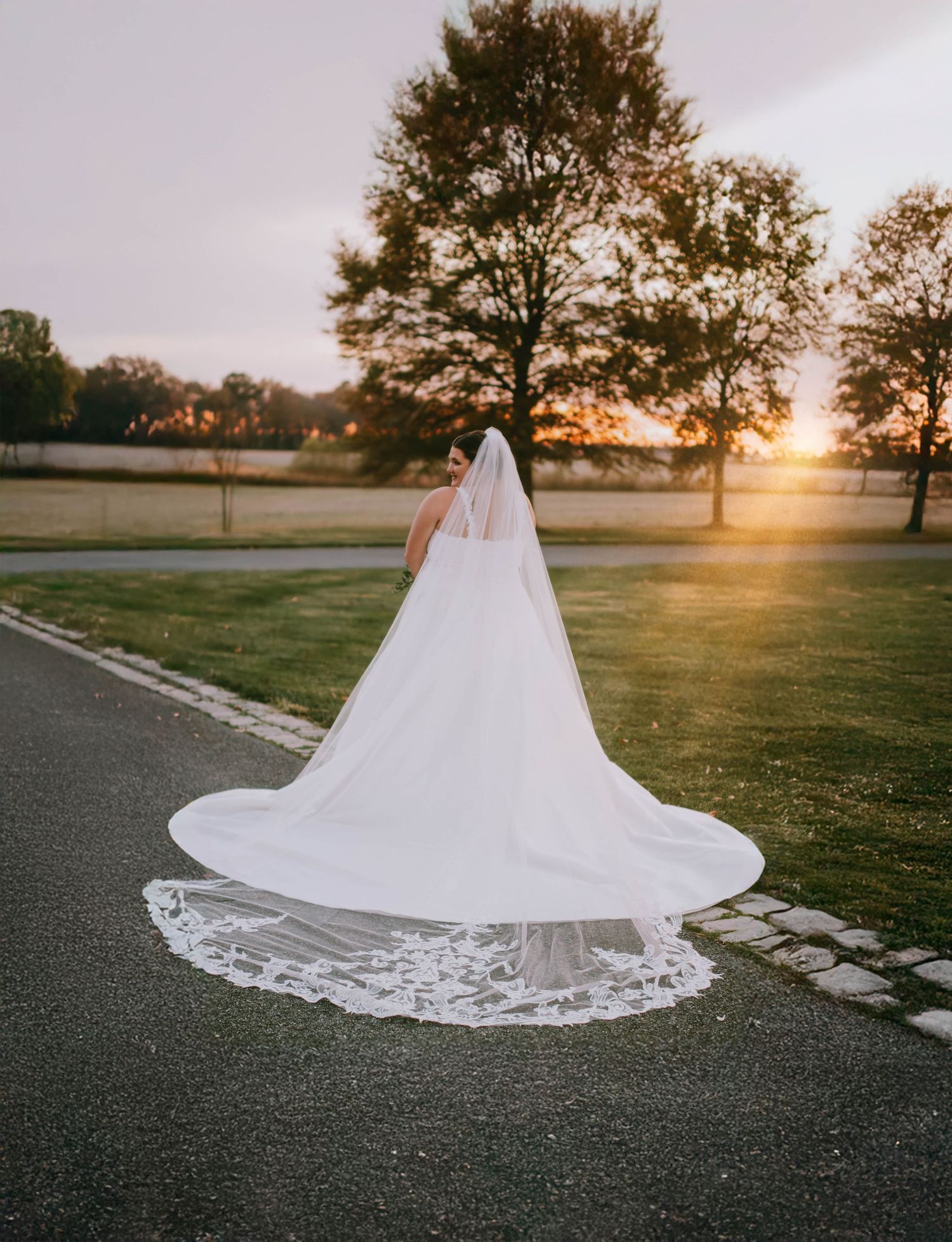 Stunning bridal train with lace details spreads across pavement during golden hour.