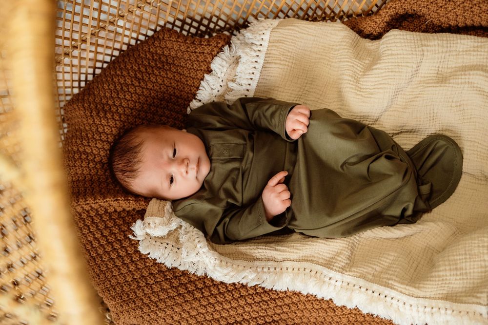 A collection of vintage-style baby portraits showing an infant in olive and cream colored outfits on textured backgrounds.