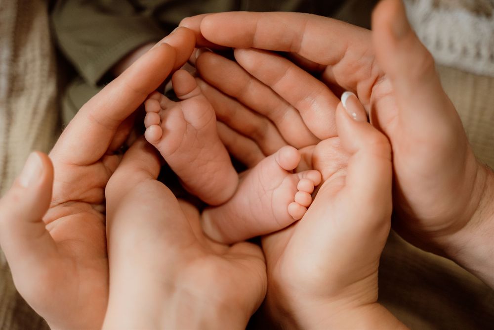 A close-up of tiny baby toes being gently held by adult hands in a tender moment.