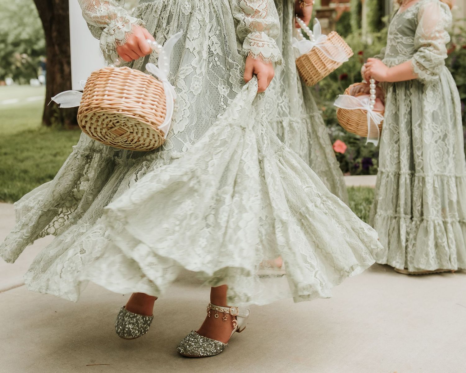 Detail shot of sage green and white lace dresses with wicker baskets.