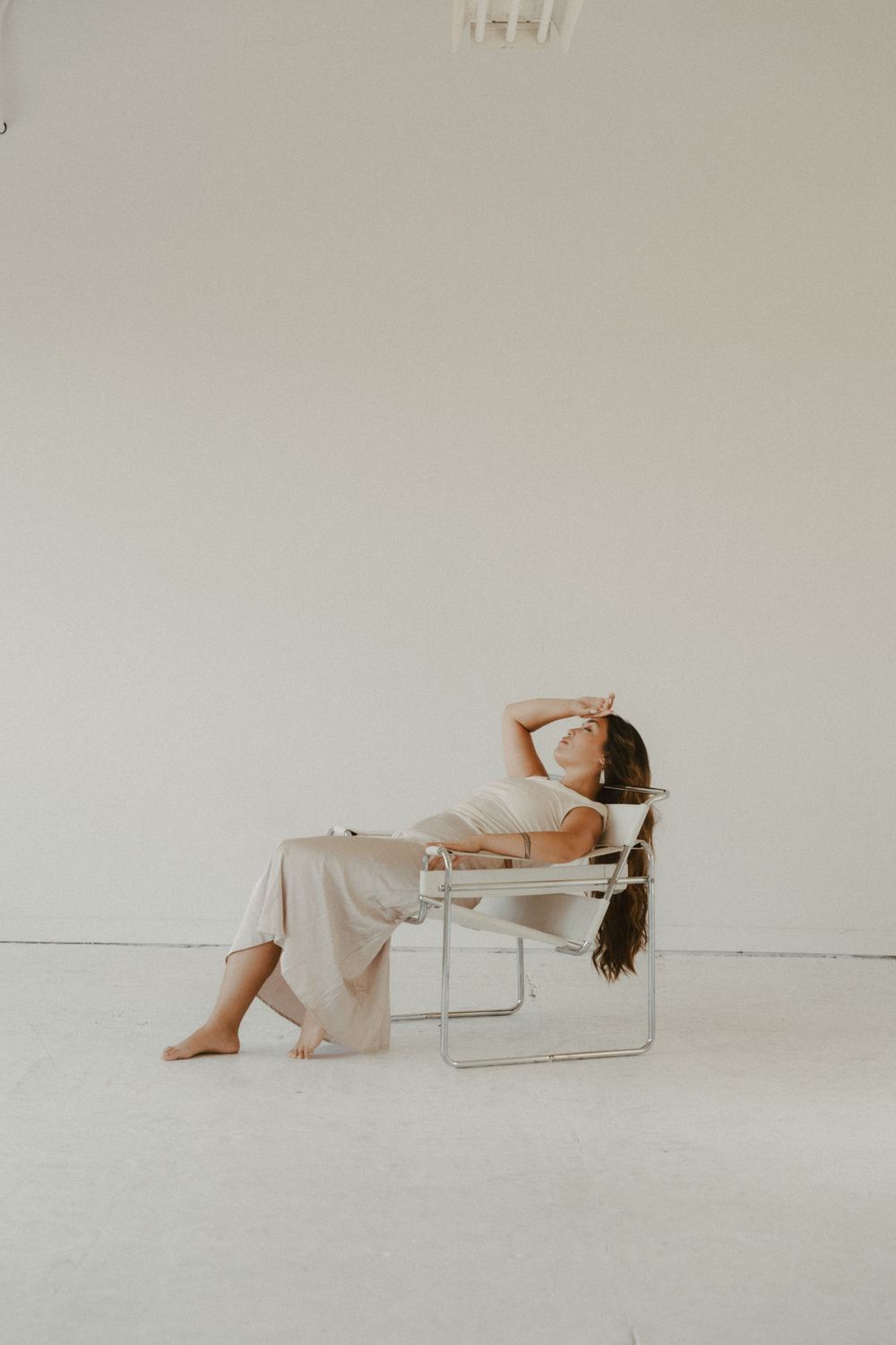 A woman reclines in a modern chair against a white minimalist backdrop.