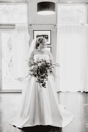 Elegant white wedding dress photographed in black and white against minimalist backdrop.