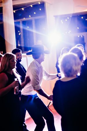 Silhouettes of party guests dancing under string lights at an evening celebration.