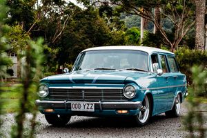Row of restored vintage American automobiles displayed on grass.