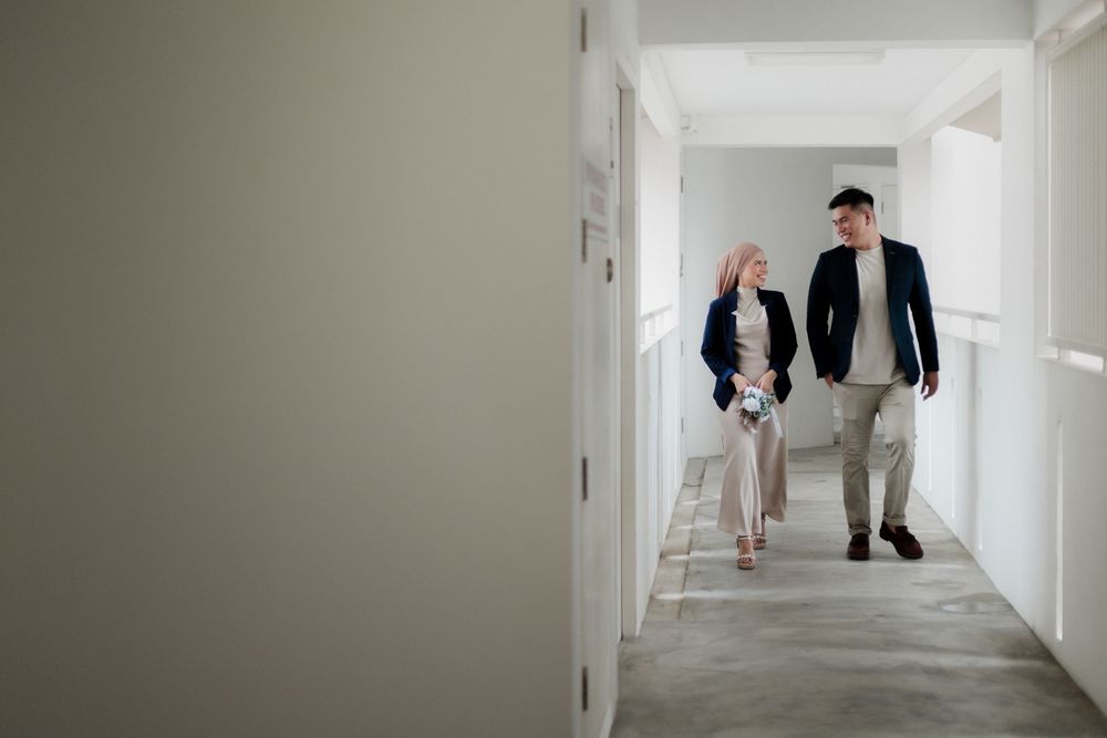 A man and woman in business attire walking and talking together in a bright modern hallway.