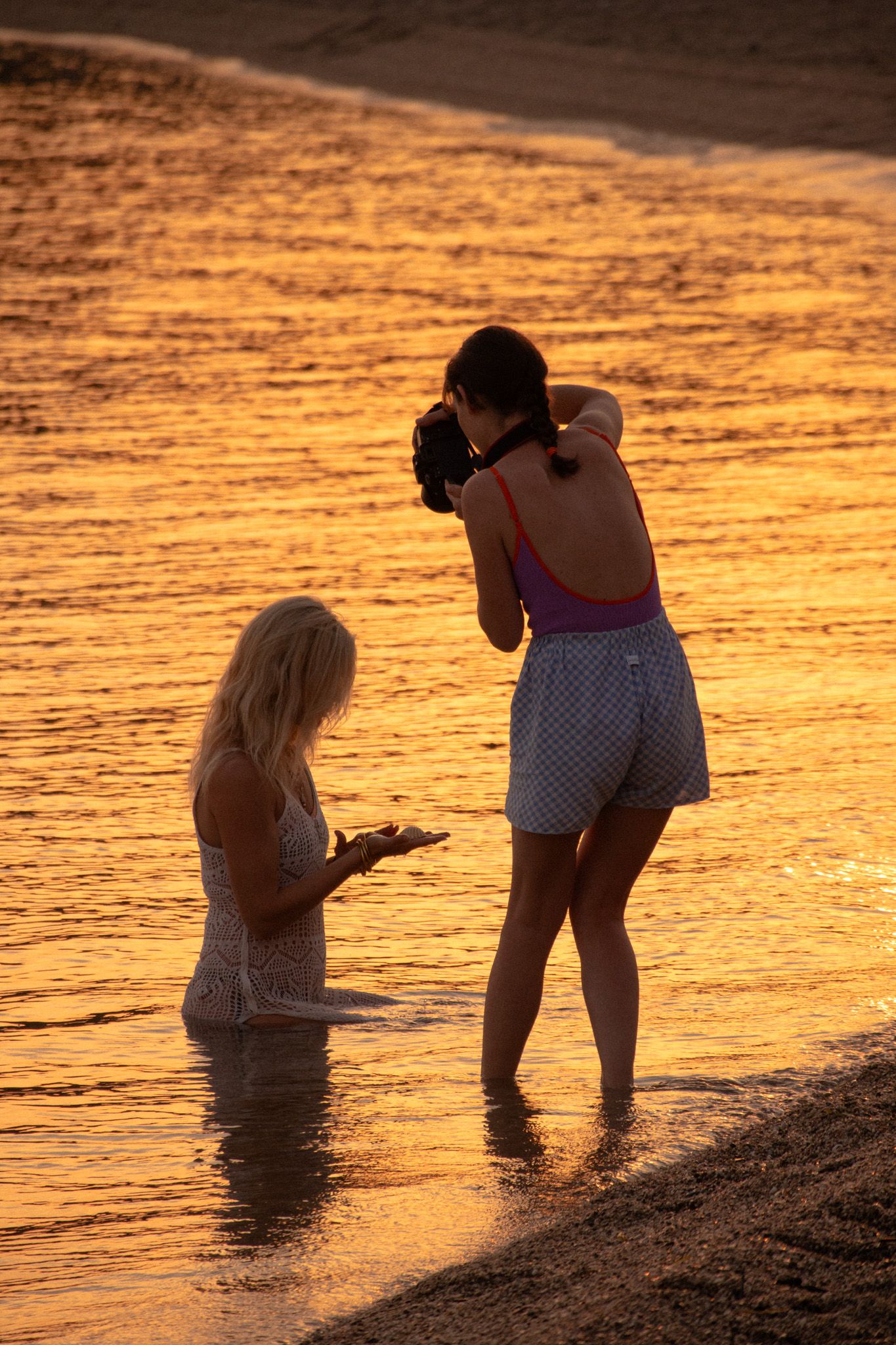 Claire photographing a woman in the mediterranean sea in the glowing light of the sunrise.
