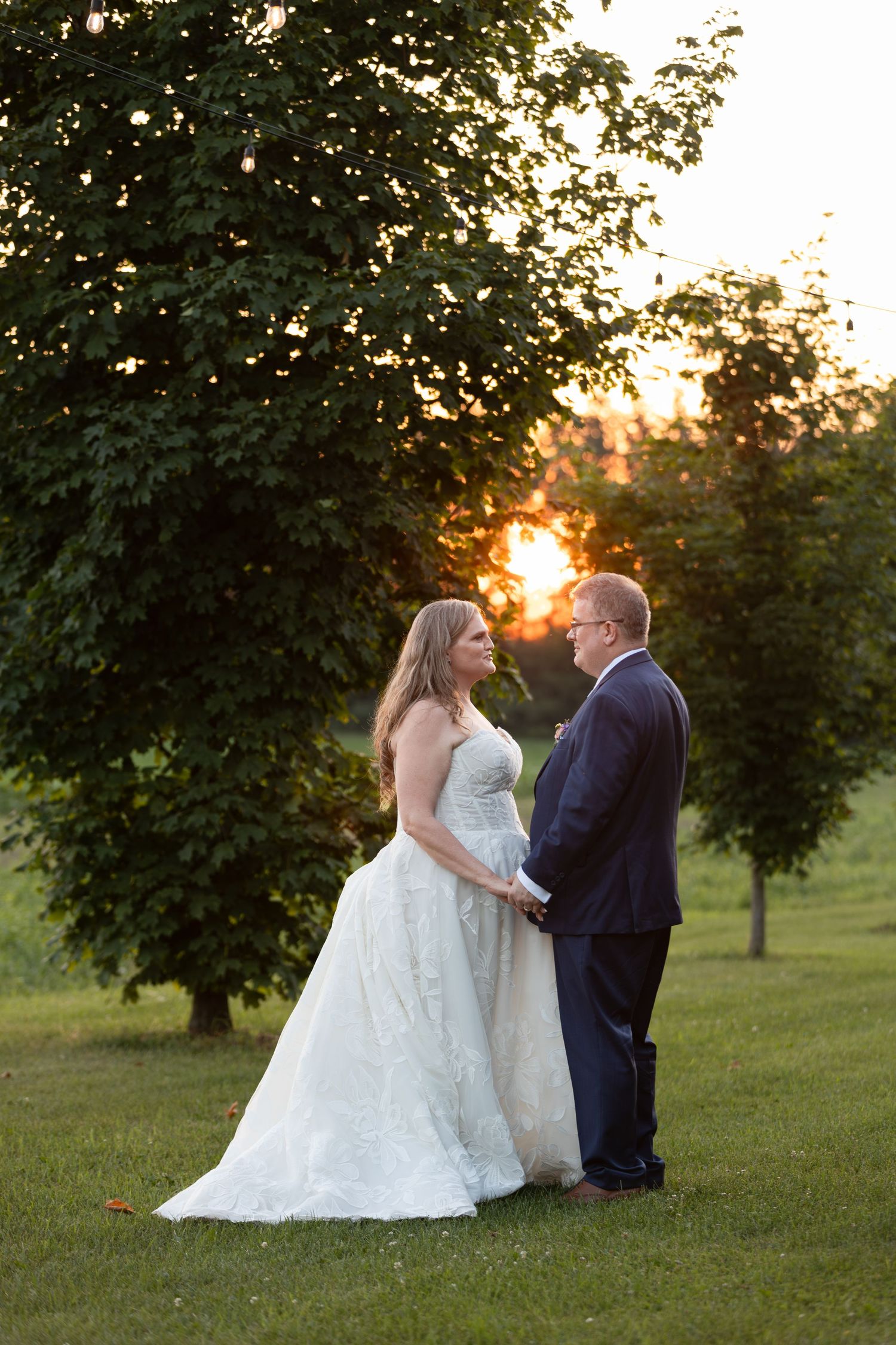 Bride and groom holding hands at sunset on a green lawn at barn swallow fields in guelph, ontario.