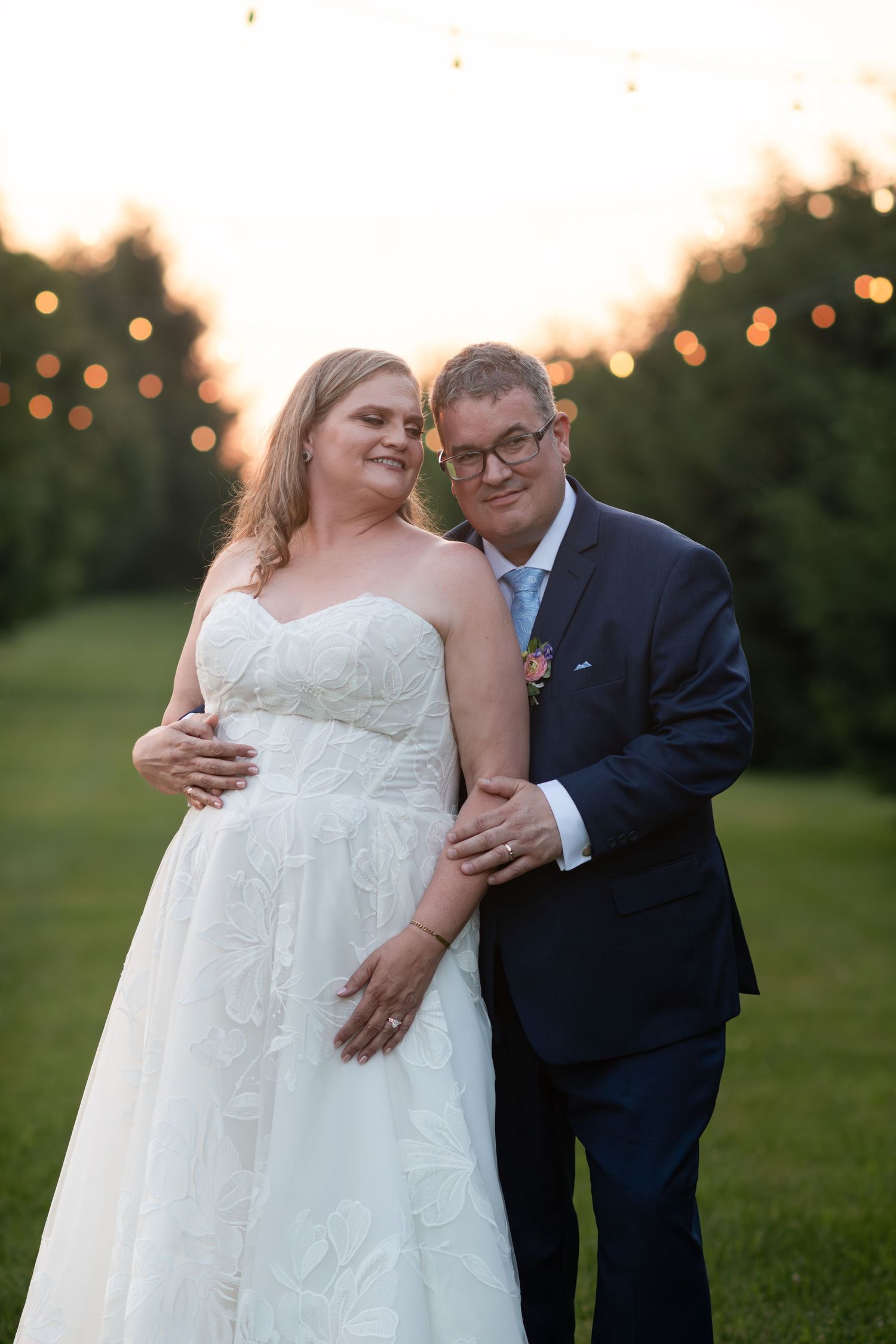 Bride and groom embracing outdoors at golden hour with bokeh string lights at barn swallow fields in guelph, ontario.