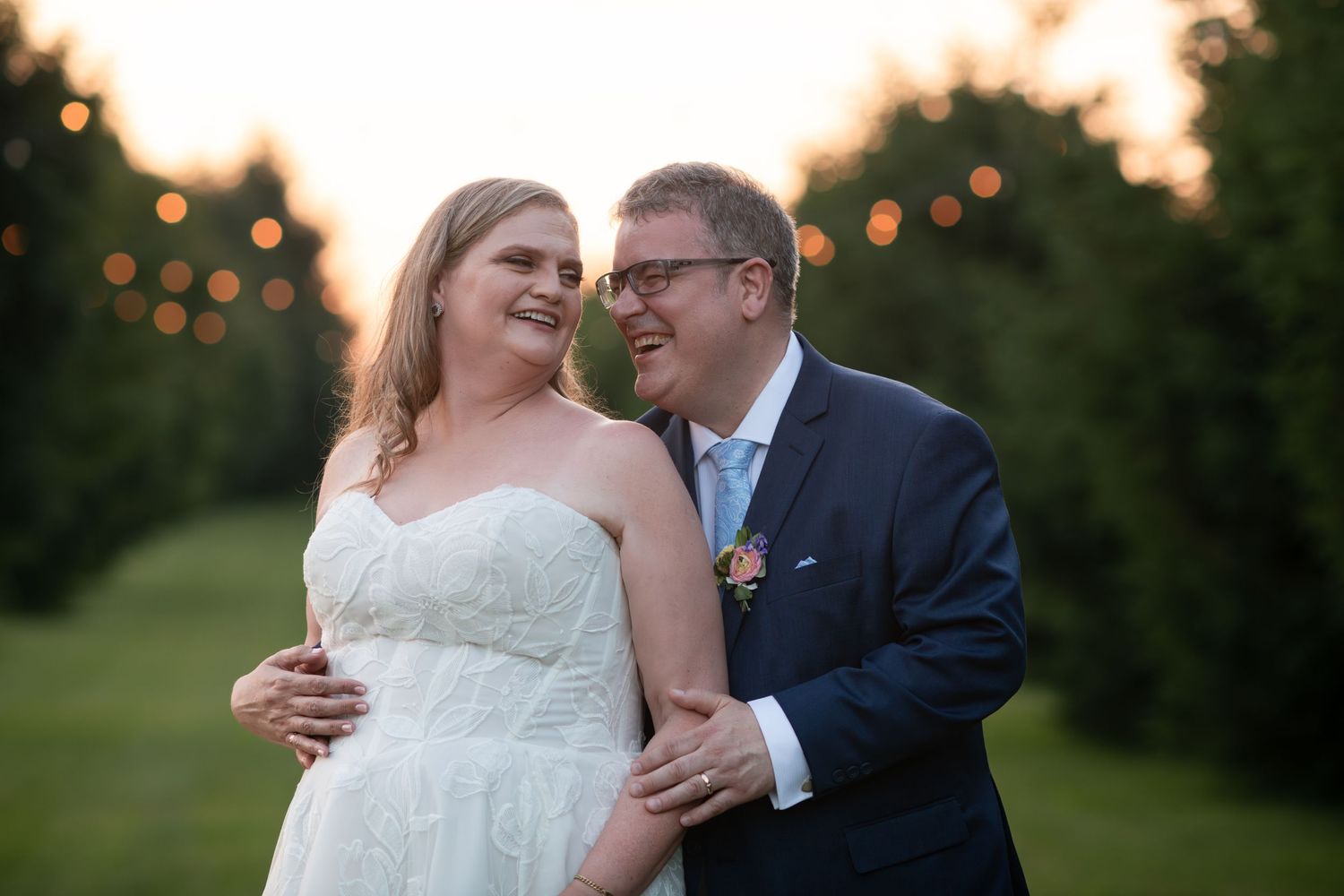 Bride and groom share a moment outdoors at golden hour, surrounded by lush greenery and string lights at barn swallow fields in guelph