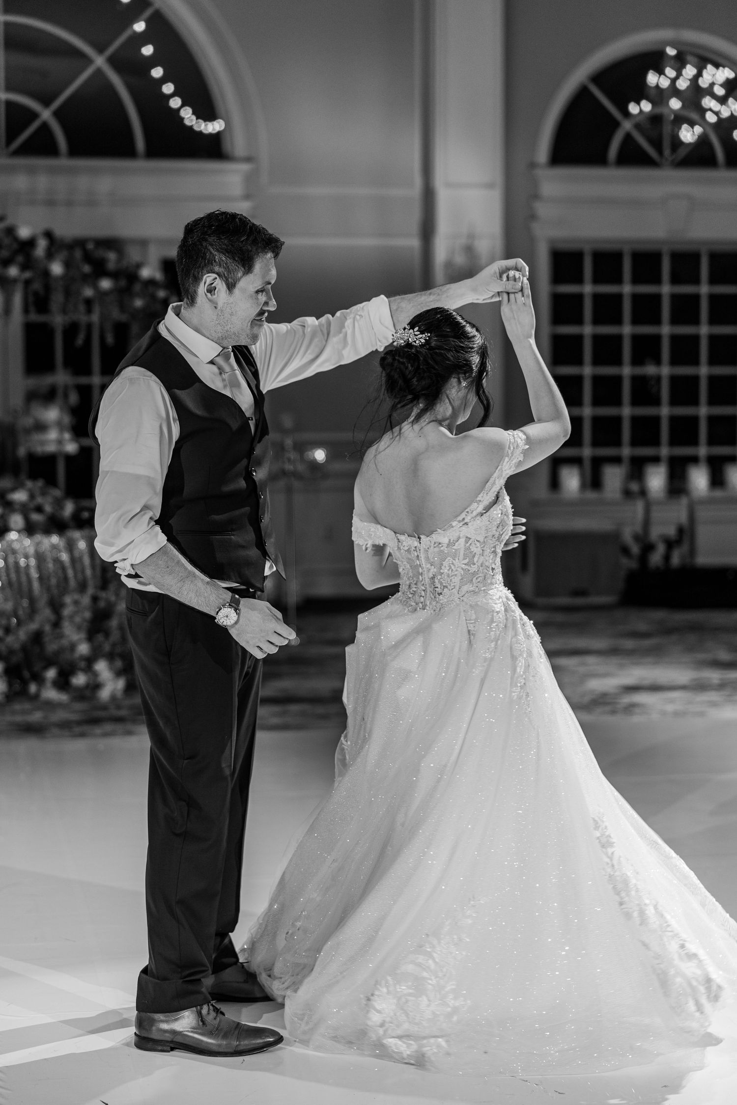 Black and white photo of bride and groom sharing their first dance at elegant wedding reception venue.