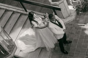 Black and white aerial photo of bride and groom sharing a romantic dance outdoors on a tiled patio.
